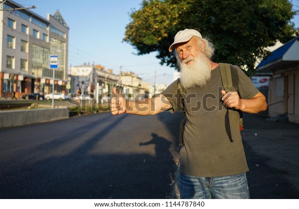 Happy old man\
with beard catching a taxi in\
city