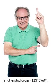 Happy Old Man Pointing Upwards. Studio Shot Over White Background.