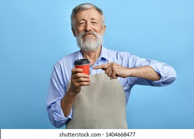 Happy Old Man Standing With Disposable Cup Of Coffee And Pointing At It Isolated On Blue Background. Good Choice.best Coffee For Old People