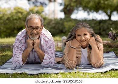 Happy old man and woman in casual lay on plaid, enjoy picnic together in park outdoor. Love, relationships at free time and weekends, retirement and lifestyle, ad and offer - Shutterstock ID 2310519153