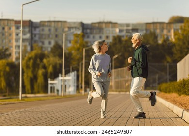 Happy old married couple learn physical vitality and longevity secret, do sport workout, have fun. Cheerful joyful older male female friends work out, run together in park on good spring or summer day