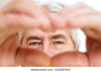 Happy Old Senior Man Making Heart Shape Hand Gesture. Look at Camera, Showing Romantic. Retired Elderly Grandparent Close Up Portrait. Symbol of Love Yourself. Doing charity Work, take Care of Health.