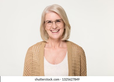 Happy old senior woman modern grandma in glasses looking at camera, smiling mature middle aged elderly lady model laughing posing for portrait isolated on white grey blank studio background