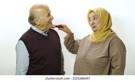 Happy Old Woman In Hijab Is Cleaning Pet Hair From Husband's Clothes With Sticky Clothing Roll.Studio Portrait Of Elderly Husband And Wife Isolated On White Background.Cat,dog And Pet Hair On Clothes.