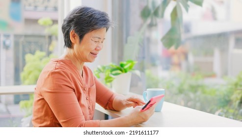 Happy Old Woman With Mobile Phone Watching Video In The Coffee Shop