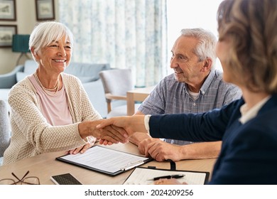 Happy old woman shaking hands with medical adviser for health insurance while sitting at home. Senior couple signing deal for insurance with financial advisor after retirement. 