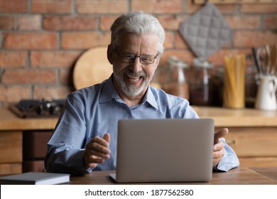 Happy Older Businessman In Eyeglasses Looking At Laptop Screen, Feeling Excited Of Reading Email With Good News. Laughing Middle Aged Man Enjoying Online Web Camera Video Call Talk With Grown Children