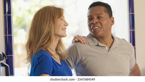 Happy Older Caucasian And African American Husband And Wife Standing In Their Kitchen Smiling. Senior Mixed Race Couple Homeowners