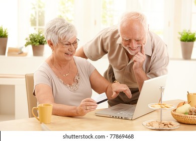 Happy Older Couple Doing Online Shopping, Laughing Wife Pointing At Screen Of Laptop Computer.?