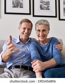 Happy Older Couple Greeting Family Making Online Video Call Talking To Web Cam. Middle Aged Old Grandparents Enjoying Virtual Distance Meeting Chat, Laughing, Looking At Camera At Home, Webcam View