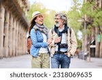 Happy older couple having fun walking outdoors in city. Retired people enjoying a sightseeing walk on street in spring. Mature couple relationships and vacations of pensioners.