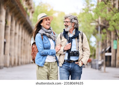 Happy older couple having fun walking outdoors in city. Retired people enjoying a sightseeing walk on street in spring. Mature couple relationships and vacations of pensioners. - Shutterstock ID 2318069635