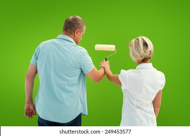 Happy Older Couple Painting White Wall Against Green Vignette