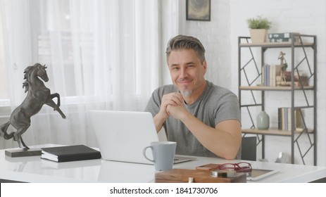 Happy Older Man With Gray Hair Working At Home In Home Office With Laptop Computer.