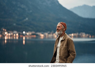 Happy older man standing in nature park enjoying natural park landscape. Smiling mature active traveler exploring camping tourism nature lake and mountains travel journey feeling freedom. - Powered by Shutterstock