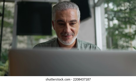 Happy Older Man Using Laptop Computer At Coffee Shop. Closeup Face Of A Senior Entrepreneur Looking At Screen Working Remotely At Cafe Place