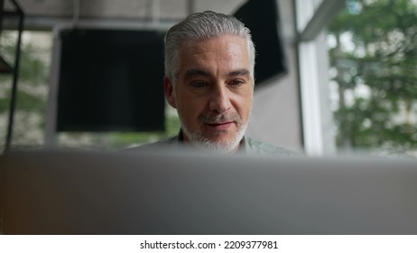 Happy Older Man Using Laptop Computer At Coffee Shop. Closeup Face Of A Senior Entrepreneur Looking At Screen Working Remotely At Cafe Place