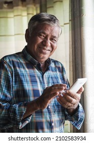Happy older man while using smartphone at home.