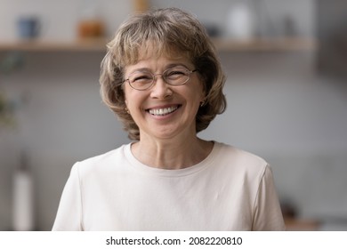 Happy older mature 60s woman indoor head shot portrait. Cheerful elder lady wearing eye glasses, casual, looking at camera with toothy smile, posing at home, laughing. Video call screen - Shutterstock ID 2082220810