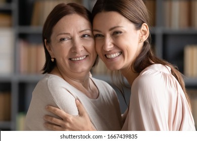 Happy Older Mature Brunette Woman Touching Heads With Smiling Grownup Child. Head Shot Close Up Attractive Two Generations Women Looking Away, Having Fun Together, Enjoying Free Leisure Time.