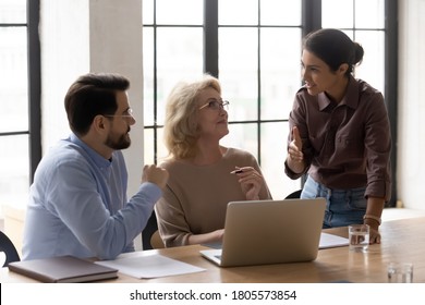 Happy Older Mature Female Company Leader Developing Strategy With Motivated Skilled Young Multiracial Employees At Brainstorming Meeting. Diverse Business People Discussing Online Project In Office.