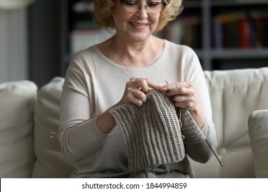 Happy older senior 60s woman in eyeglasses knitting warm clothing with woolen threads, sitting alone on comfortable sofa in living room, elderly retired people hobby activity lifestyle concept. - Powered by Shutterstock