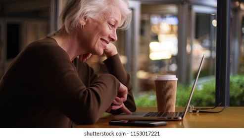 Happy Older Woman Browsing Internet In Coffee Shop With Wifi