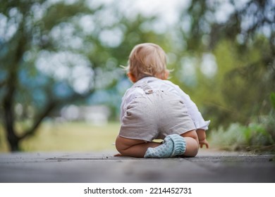 happy one year old baby boy sitting or crawling in chic festive summer clothes outdoor on the floor with magical, idyllic  flowery green garden trees in the background - Shutterstock ID 2214452731