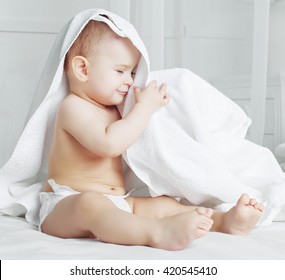 Happy One Year Old Baby Wearing Diapers With A Towel In Bed At Home