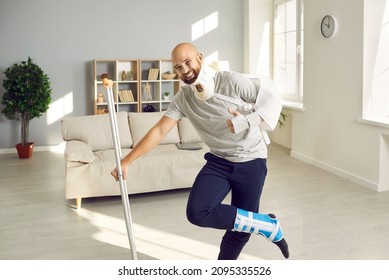 Happy optimistic man with multiple physical injuries after car crash accident standing in living room, leaning on crutch, smiling and giving thumbs up to show how much he's enjoying sick leave at home