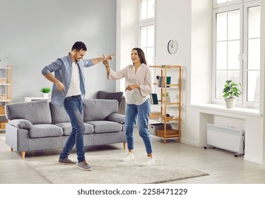 Happy overjoyed laughing young couple homeowners having fun dancing at home in living room celebrating moving into new apartment or enjoying a good mood. People, couple and family concept. - Powered by Shutterstock