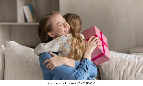 Happy overjoyed mom holding pink gift box, hugging little daughter, tightening kid woth gratitude, love, thank, celebrating mothers day, birthday, 8 march, special date, enjoying family celebration