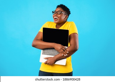 Happy Overweight Black Woman Hugging Laptop Computer With Blank Screen Posing Standing Over Blue Studio Background. Online Technology. Website Advertisement Concept. Mockup