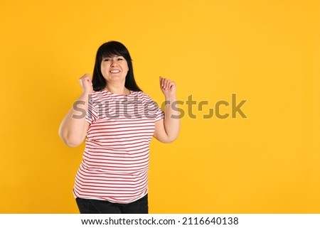 Happy overweight mature woman on orange background, space for text