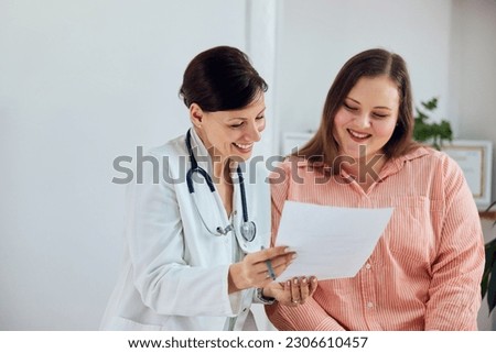 A happy overweight woman is satisfied with her weight loss program results and sitting with a female nutritionist.