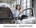 Happy Owner. Overjoyed Lady Holding Keys Of Her New Car After Buying, Cheerful Brunette Woman Standing Near Vehicle In Dealership Center And Raising Fist With Excitement, Copy Space