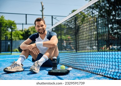 Happy paddle tennis player relaxing on the court and looking at camera. - Powered by Shutterstock