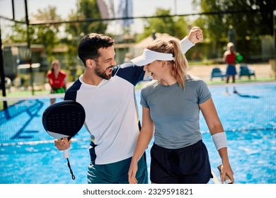 Happy paddle tennis players celebrating victory after playing doubles on outdoor court.  - Powered by Shutterstock