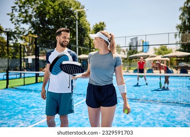 Happy paddle tennis players communicating during a match on outdoor court. - Powered by Shutterstock