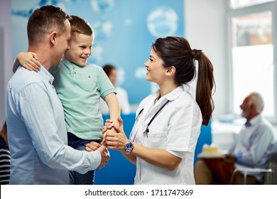 Happy paediatrician talking to a small boy who came with his father in the hospital. 