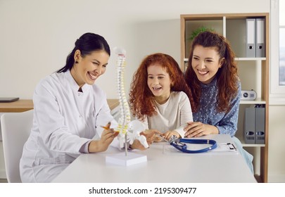 Happy Parent And Child Visit Family Doctor. Cheerful Little Kid Learning About Human Spine And Skeleton. Mom And Daughter Looking At Anatomical Spinal Model And Laughing. Health, Medicine, Fun