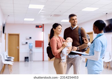 Happy parents with baby talking to nurse in hallway at pediatric clinic. - Powered by Shutterstock