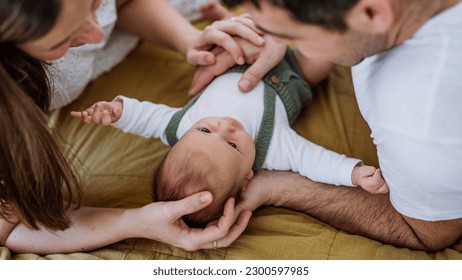 Happy parents cuddling with their newborn baby. - Shutterstock ID 2300597985