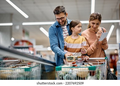Happy parents with daughter going through checklist while buying in supermarket. - Shutterstock ID 2207692509