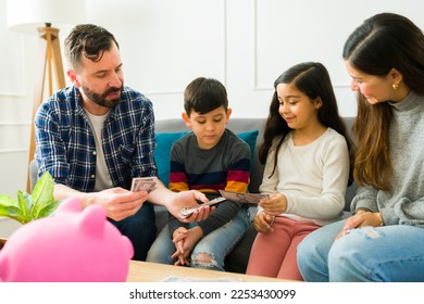 Happy parents giving allowance money to their little kids and teaching about savings and financial education - Shutterstock ID 2253430099