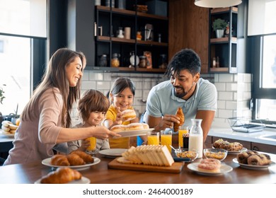 Happy parents having breakfast with children, small lovely boy and girl in the kitchen. - Powered by Shutterstock