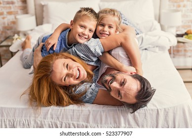 Happy Parents And Kids Enjoying Their Morning In Bed