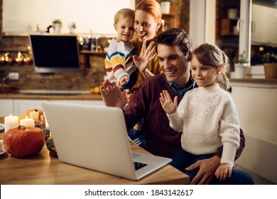 Happy parents and kids waving while having video call over laptop on Thanksgiving at home.  - Powered by Shutterstock