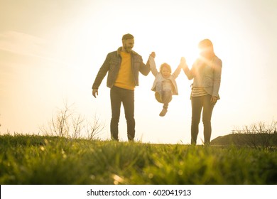 Happy parents playing with their daughter in the park. Space for copy. - Shutterstock ID 602041913