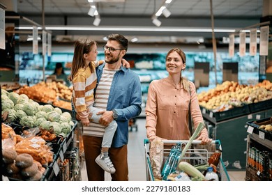 Happy parents with small daughter shopping in supermarket.